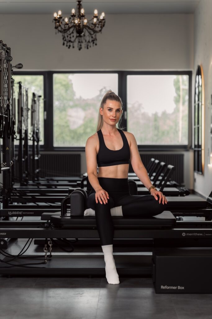Gr&uuml;nderin Marleen sitzt auf einem Reformer im Pilates-Studio Flow your core